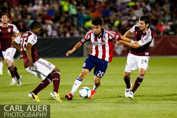 May 25th, 2013 - Chivas USA midfielder Carlos Alvarez (20) dribbles the ball against the defense by Colorado Rapids midfielder Nathan Sturgis (24) and forward Deshorn Brown (26) in the second half of the MLS match between Chivas USA and the Colorado Rapids at Dick's Sporting Goods Park in Commerce City, CO