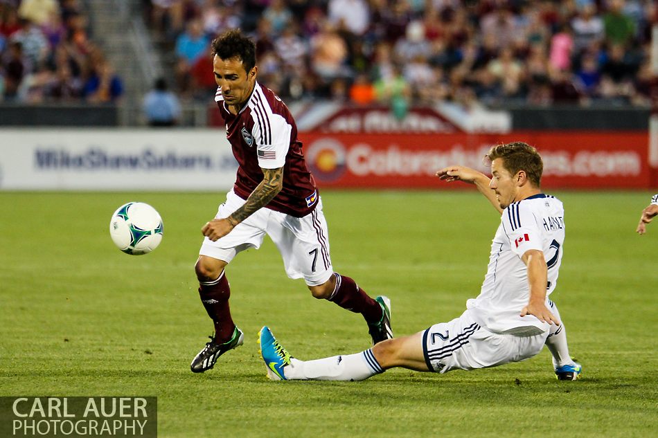 August 17th, 2013 - Colorado Rapids forward Vicente Sánchez (7) attempts to avoid a tackle by Vancouver Whitecaps FC defender Jordan Harvey (2) in the first half of the Major League Soccer match between the Vancouver Whitecaps FC and the Colorado Rapids at Dick's Sporting Goods Park in Commerce City, CO